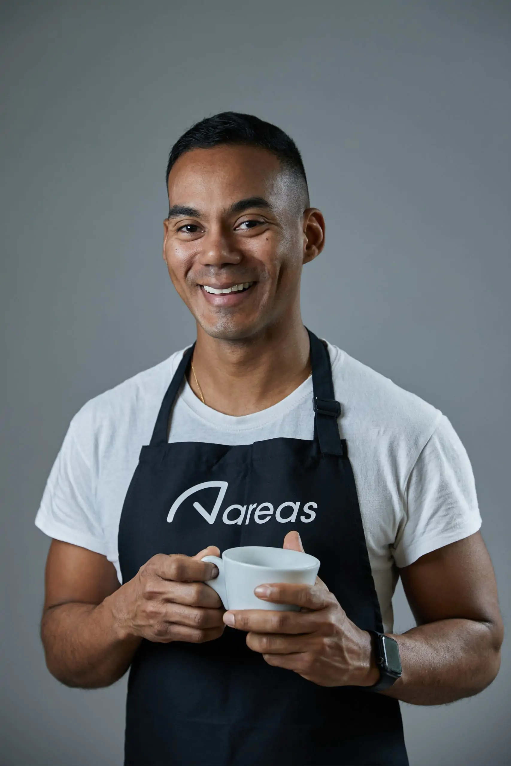 Smiling employee wearing an apron and holding a cup of coffee