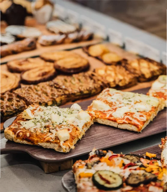 Assorted slices of focaccia and flatbread displayed on a wooden board.